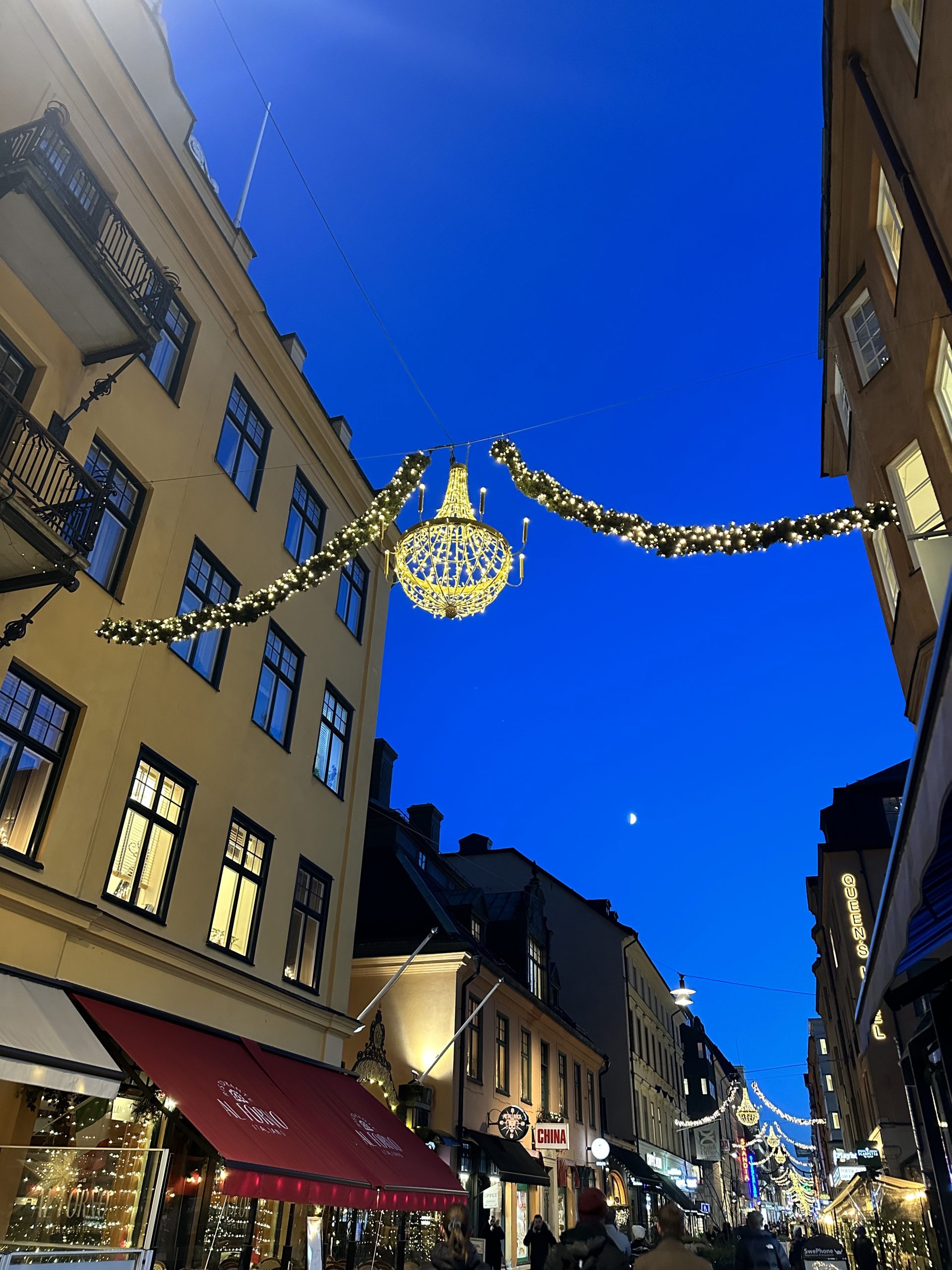 Hängande julbelysning mellan husfasader med med blå himmel